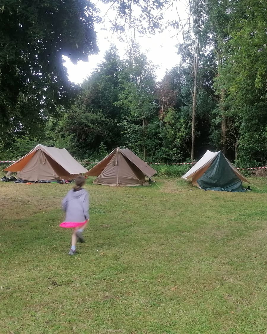 Un enfant court vers les tentes au camping nature